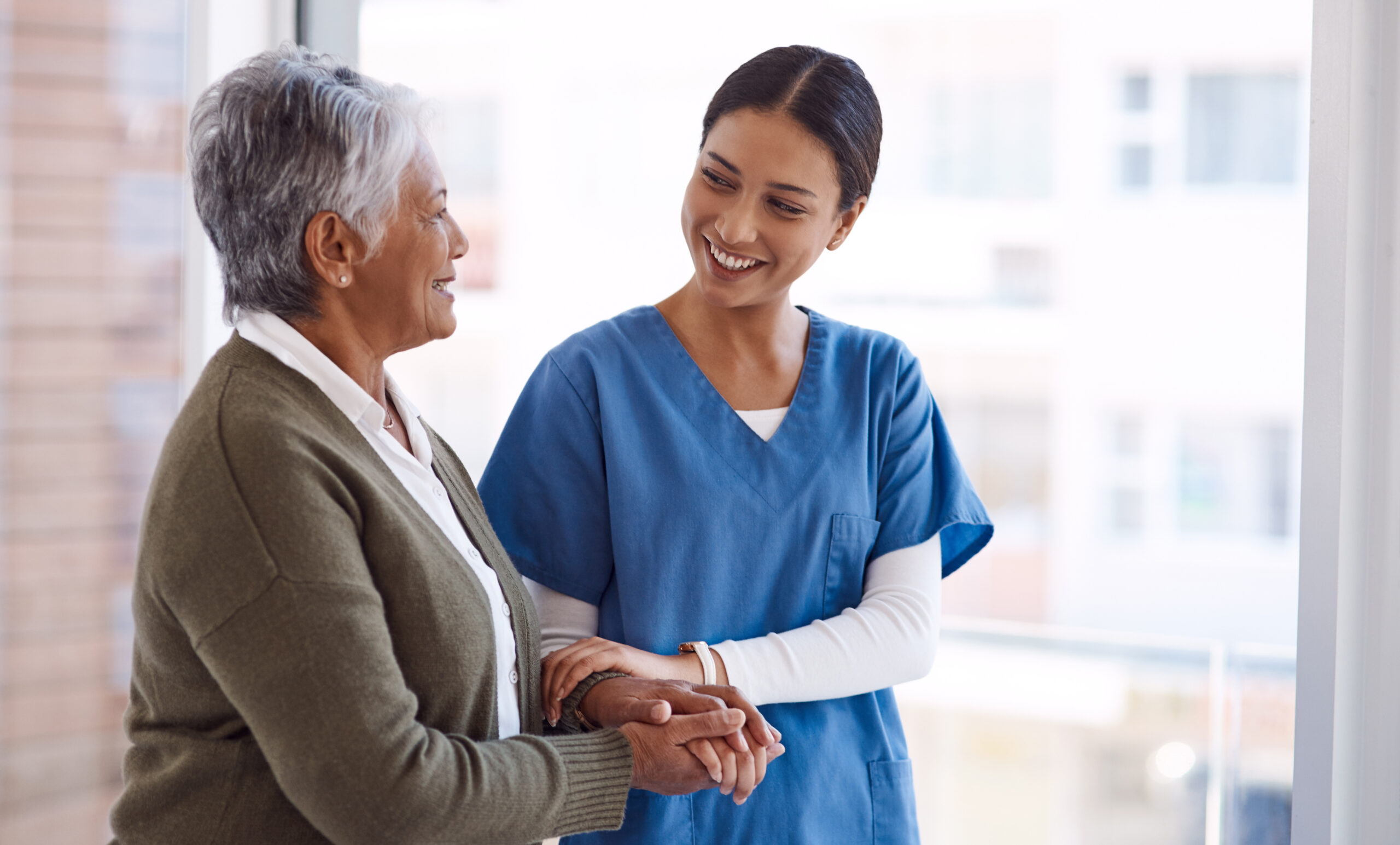 A female caregiver hold hand of senior woman