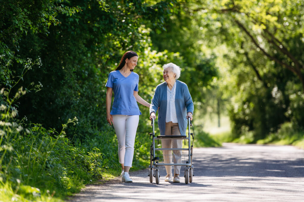 Caregiver pushing senior woman in wheelchair at park like setting 