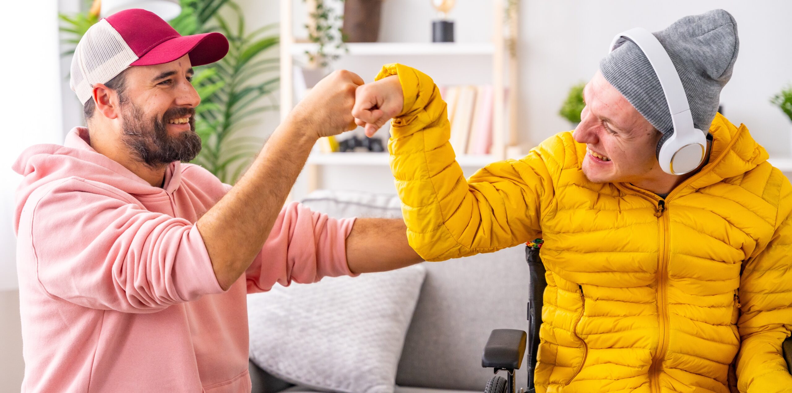 Alastar Family Senior Home Care-disabled man and friend giving each other a fist bump Disabled man and friend feeling happy and giving each other a fist bump