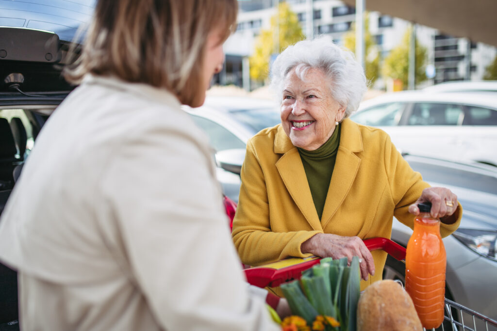 Caregiver helps senior lady load groceries in car