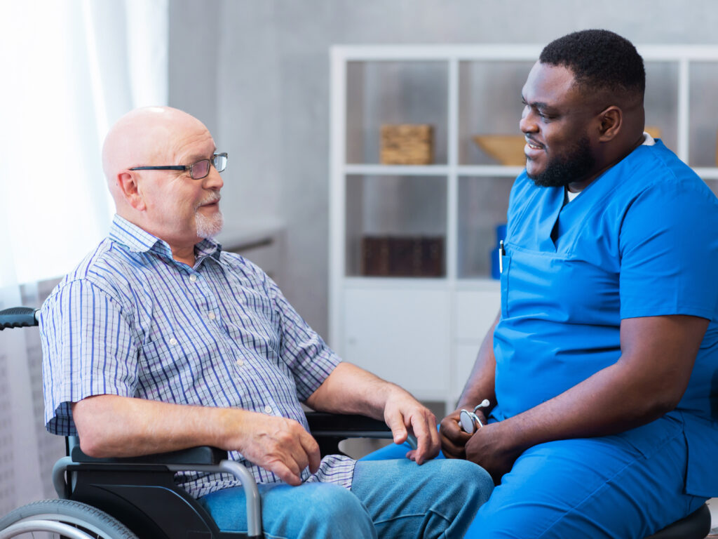 Professional caregiver assists an elderly man in wheelchair.
