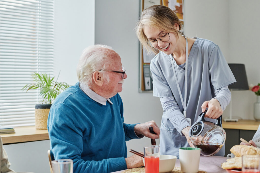 A caregiver pouring coffee for senior man